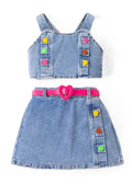 A two-piece toddler girl's denim outfit set featuring a sleeveless top with colorful button details and a matching denim skirt with a bright pink heart-shaped belt.